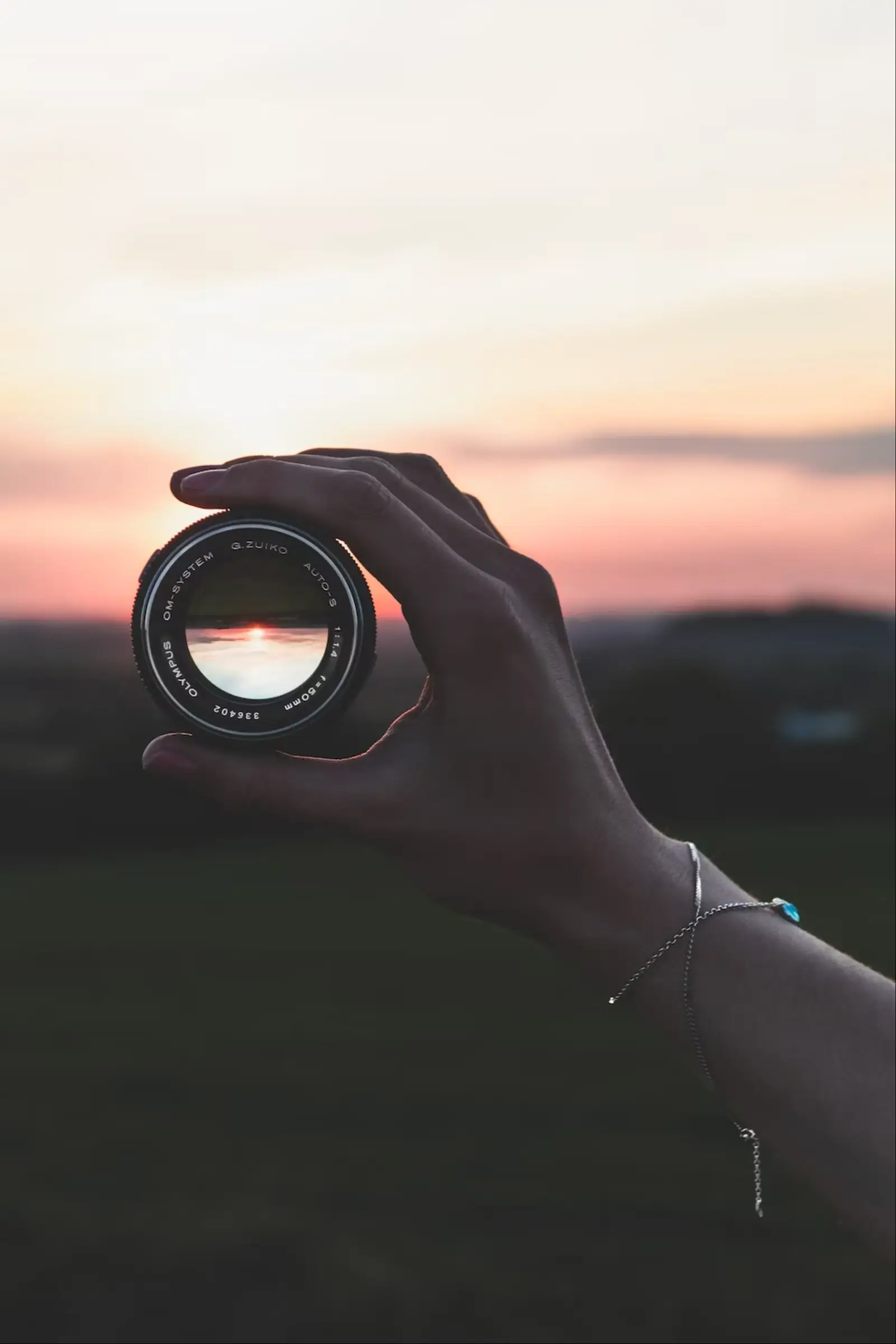 Un objectif photo tendu vers un coucher de soleil